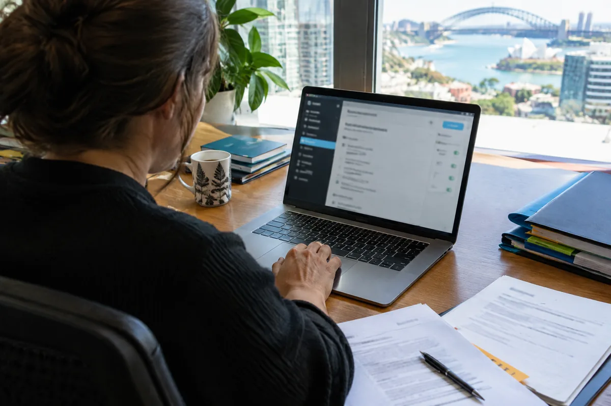 Website administrator checks settings on a laptop overlooking Sydney Harbour